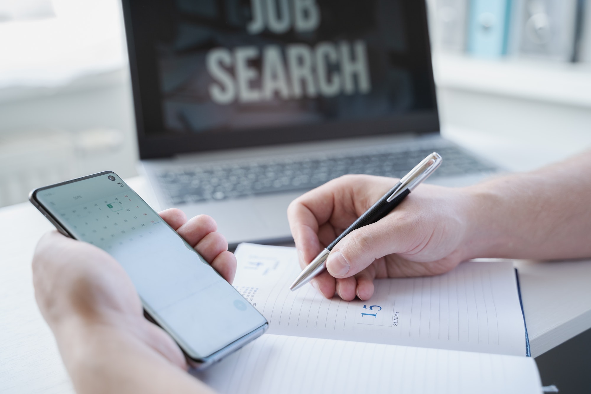 Person concentrating on job search for development surveyor positions highlight importance of optimising your job postings with laptop in background.